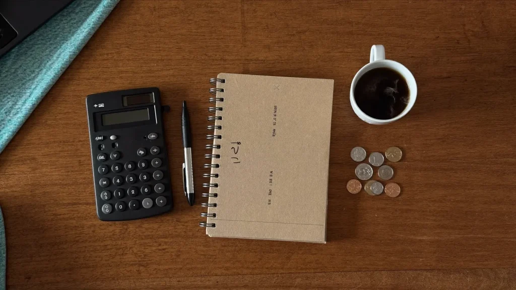 Flat-lay of a desk with calculator, notebook and coins - comparing domain prices in South Africa