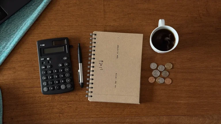 Flat-lay of a desk with calculator, notebook and coins - comparing domain prices in South Africa